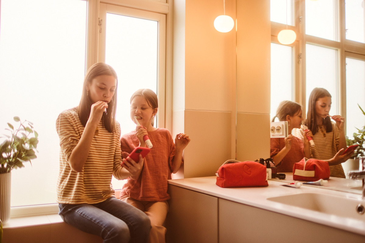 To personer pusser tennene og ser på telefonen.