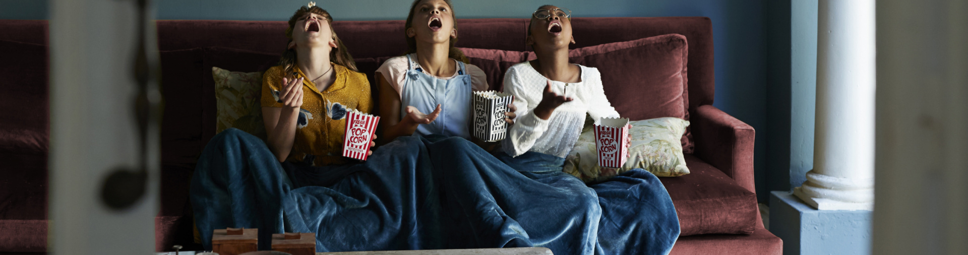 Tween girls hanging out and eating popcorn together in bohemian style home